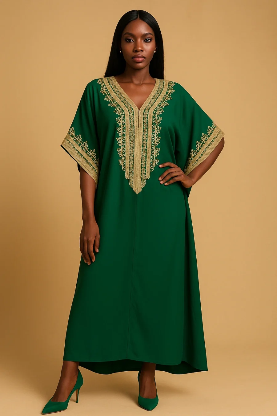 Femme ivoirienne élégante portant un caftan marocain vert émeraude avec broderie dorée artisanale, coupe ample et manches papillon, posant dans un studio beige avec escarpins assortis.